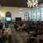 La Imagen Muestra A Un Gran Número De Personas Sentados En Una Sala. Hay Tres Personas En Una Gran Mesa, Hablando O Exponiendo Cosas Al Resto, Que Son El Público.
La Imagen Muestra A Un Gran Número De Personas Sentados En Una Sala. Hay Tres Personas En Una Gran Mesa, Hablando O Exponiendo Cosas Al Resto, Que Son El Público.